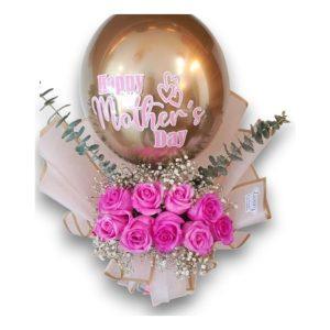Arreglo floral con rosas rosadas, decorado con gypsophila, eucalipto y un globo dorado personalizado para el Día de las Madres.